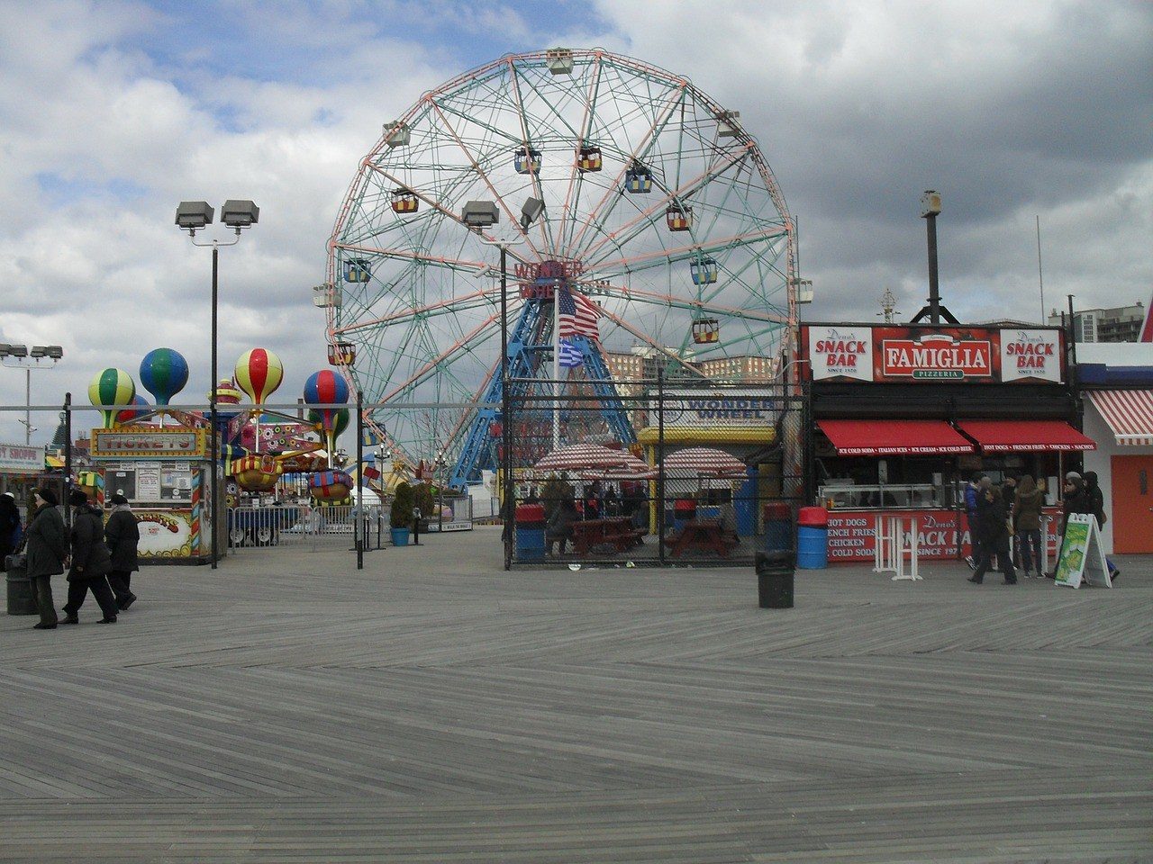 Le boardwalk de Coney Island, ses planches en bois et la grande roue Wonder Wheel derrière les stands