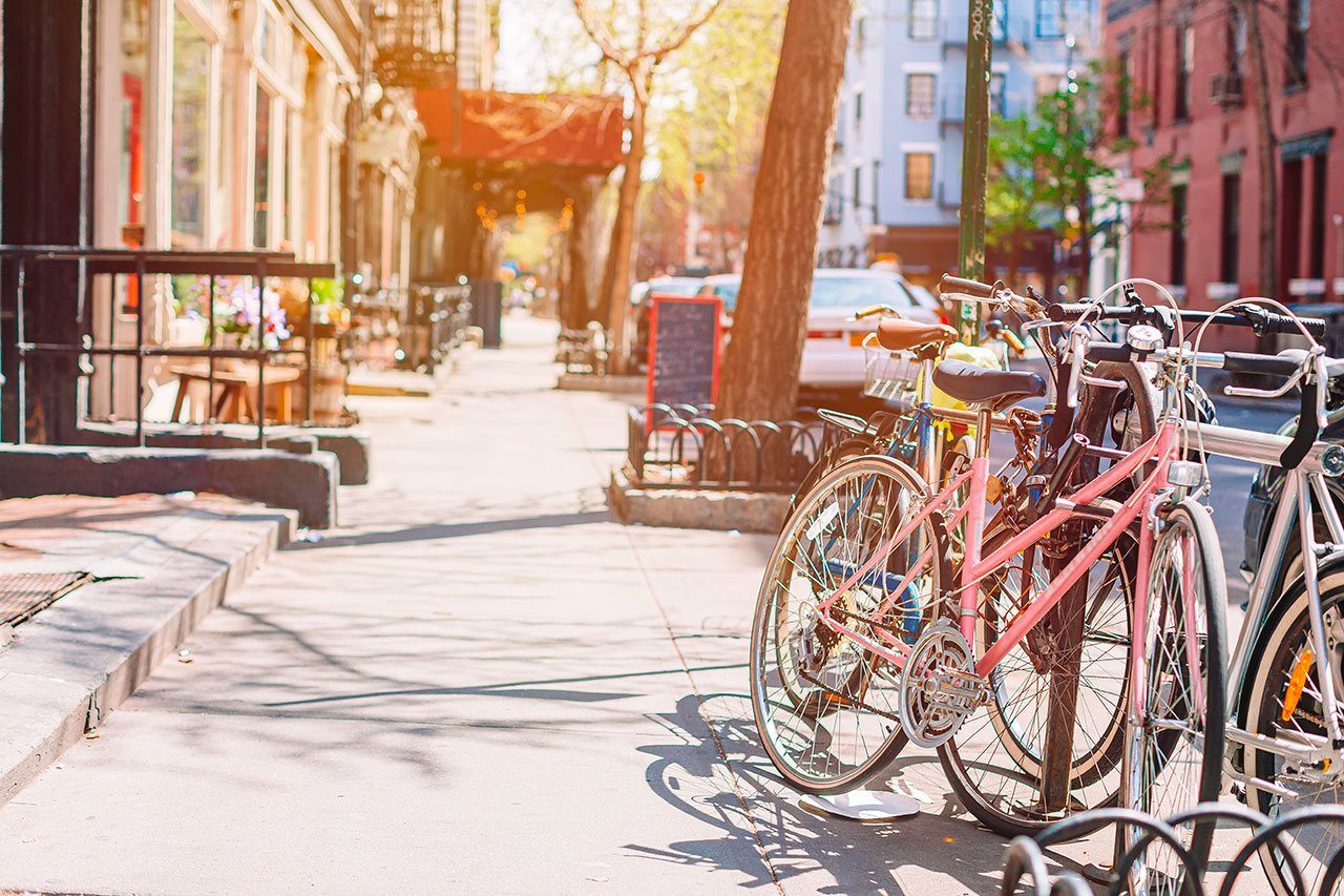 Trottoir ensoleillé bordé d'arbres et de vélos garés dans une rue résidentielle de Manhattan