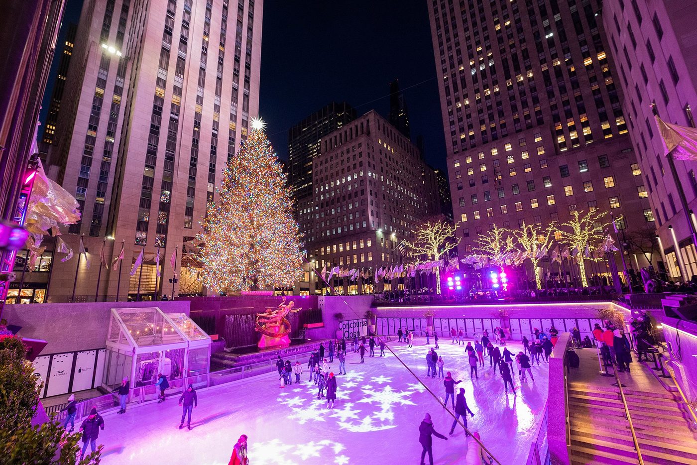 Le sapin de Noël du Rockefeller Center illuminé la nuit, au-dessus de la patinoire et de la statue dorée de Prométhée