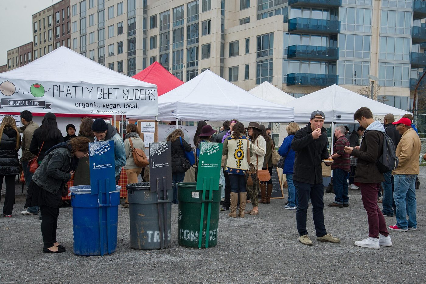 Stands sous tentes blanches et visiteurs qui mangent debout au marché Smorgasburg à Brooklyn